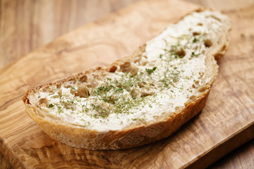 rustic wheat bread with butter and herbs on wood board