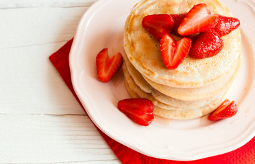 Pancakes with strawberry on a white wooden table. Top view. Selective focus.