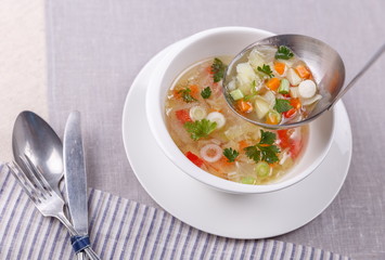 Fresh vegetable soup made of cabbage, carrot, potato, red bell pepper, tomato in bowl