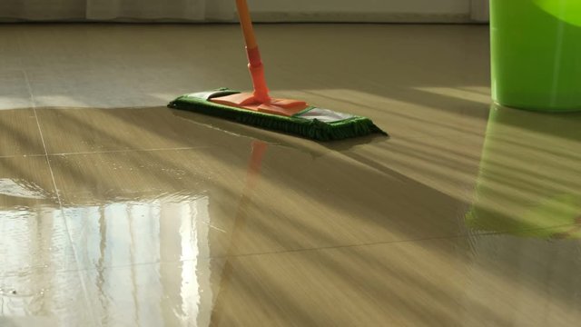 Woman cleaning and wipes the floor with a rag. Young woman is cleaning in the kitchen before the arrival of guests. Female wipes with a cloth.