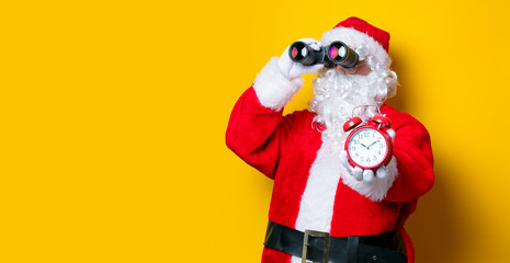 Santa Claus holding binoculars and alarm clock