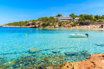 Boat on turquoise sea in Cala Portinatx bay, Ibiza island, Spain