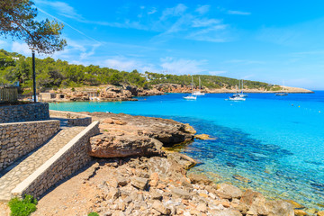 Coastal walkway along beautiful Cala Portinatx bay with azure sea water, Ibiza island, Spain