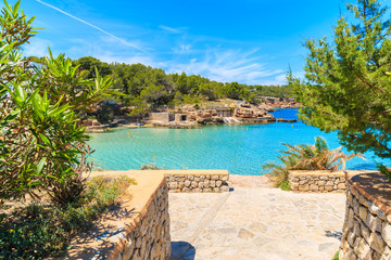 View of coastal promenade along blue sea in Cala Portinatx bay, Ibiza island, Spain
