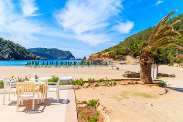 Restaurant table on sunny terrace on Cala Benirras beach, Ibiza island, Spain