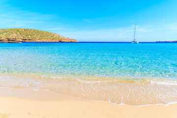 Fototapeta na wymiar Beautiful sandy Cala Comte beach and catamaran boat on sea, Ibiza island, Spain