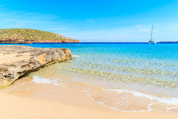 Beautiful sandy Cala Comte beach and catamaran boat on sea, Ibiza island, Spain