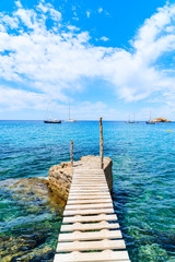 Obraz premium Mały drewniany molo w Cala d'Hort zatoce i widoku Es Vedra wyspa, Ibiza wyspa, Hiszpania