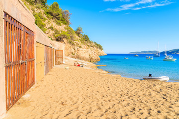 Obraz premium Boat houses on sandy beach in Cala San Vicente bay, Ibiza island, Spain