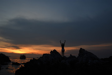 silhouette of woman watching warm sunset with seaside