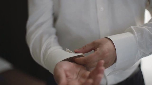 Groom wears stylish cufflinks close up