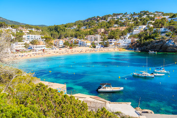 Fishing and sailing boats on blue sea water in Cala Vadella bay, Ibiza island, Spain - obrazy, fototapety, plakaty