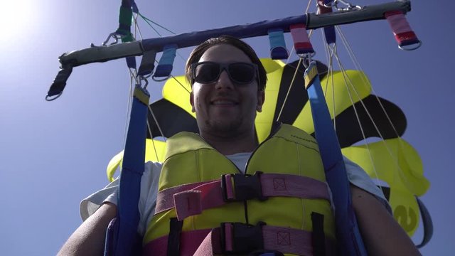 Selfy of screaming and smiling man while parascending with yellow and black parachute