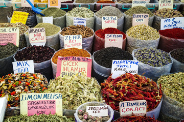 Market stall with open bags displaying variety of teas and spices.