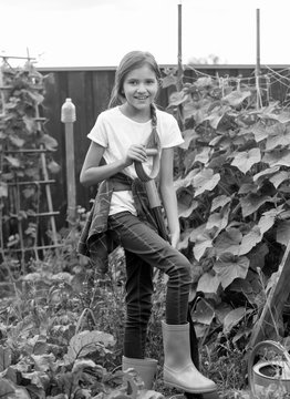 Black and white image of cute 10 year old girl working at garden and digging soil at with shovel