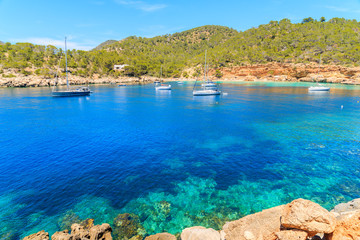 Sailing boats on blue sea water in Cala Salada bay, Ibiza island, Spain