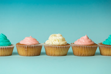 Colorful freshly baked cupcakes in row over blue background