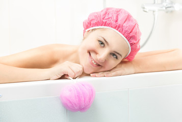 Portrait of young woman in pink shower cap posing in bath