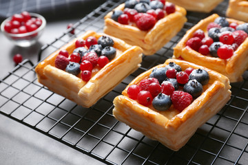 Delicious puff pastry dessert with berries on baking grid, closeup