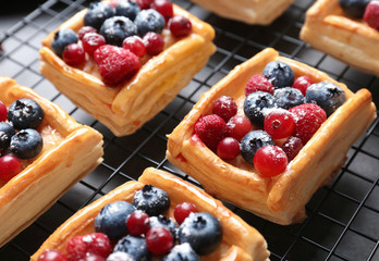 Delicious puff pastry dessert with berries on baking grid, closeup