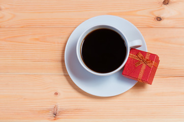 Cup of coffee and gift box on wooden background