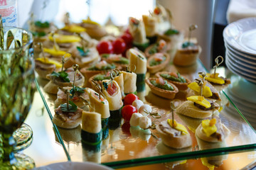 Beautifully decorated catering banquet table with burgers, profiteroles, salads and cold snacks. Variety of tasty delicious snacks on the table