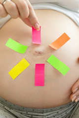 Conceptual image of pregnant woman making choice on colorful memo stickers