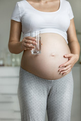 Young pregnant woman holding glass of water