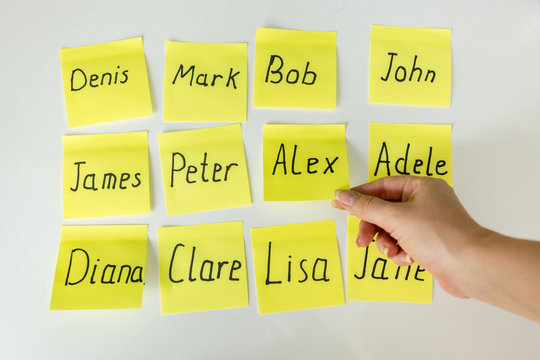 Conceptual photo of hard choice of baby's name. Closeup image of hand picking papers with names
