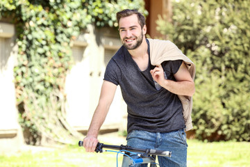 Fototapeta premium Handsome young man riding bicycle outdoors on sunny day