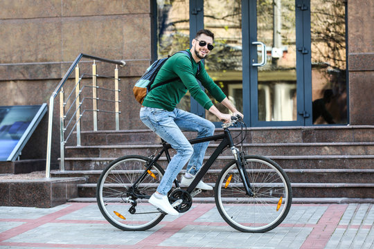 Handsome young man riding bicycle outdoors
