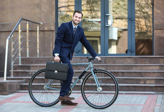Handsome young businessman with bicycle outdoors