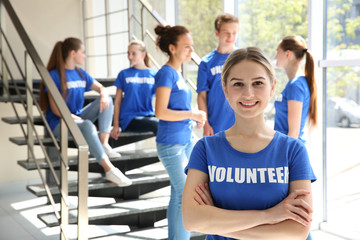 Young girl with her team near staircase indoors. Volunteering concept