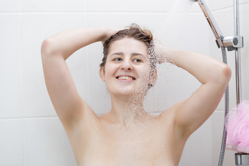 Woman washing hair with shampoo at shower