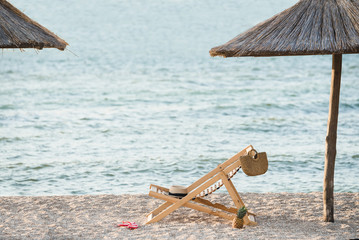 Chaise longue on the beach under the parasol