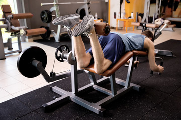 Fototapeta na wymiar Sporty young man training legs in gym