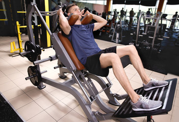 Sporty young man training legs in gym