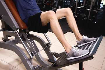 Obraz na płótnie Canvas Sporty young man training legs in gym