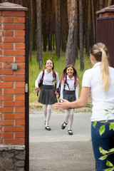 Two happy cheerful girls running to their mother after school