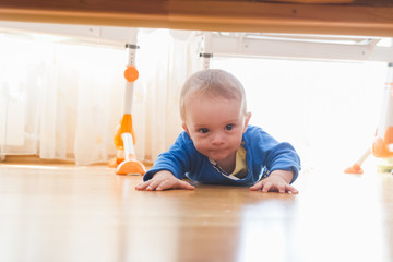 Cute baby boy crawling and looking under the bed