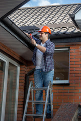 Male worker standing on step ladder in front of house