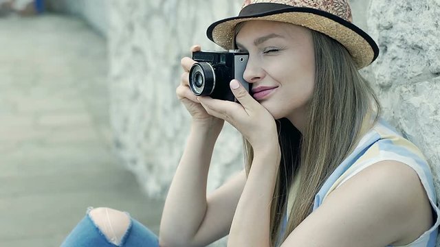 Pretty girl wearing straw hat and doing photos on old camera, steadycam shot
