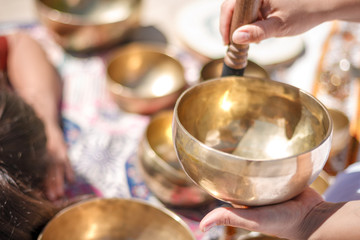 Woman playing a singing bowls also known as Tibetan Singing Bowls, Himalayan bowls. Making sound...
