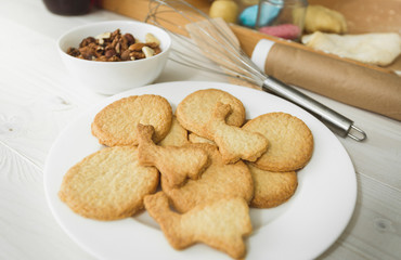 Freshly baked cookies lying on white dish at kitchen