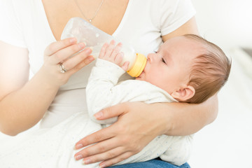 Portrait of mother giving milk from bottle to her baby