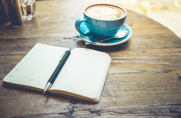 Cup of coffee latte with notepad top view on wooden table/vintage