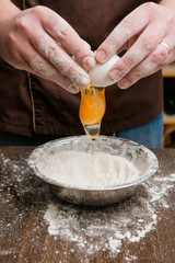Egg and flour baking process on table. Messy kitchen closeup cooking concept. Male hands making dough