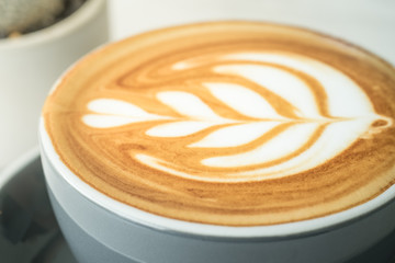 Close up dark blue coffee cup with tree shape latte art on marble table at cafe