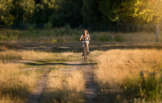 Young woman riding away on bicycle at meadow