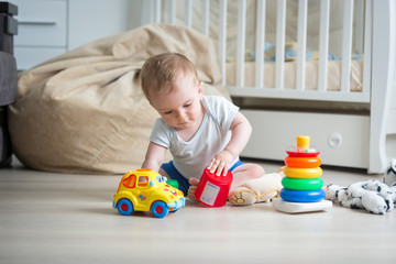 Cute toddler boy playing with toys on floor